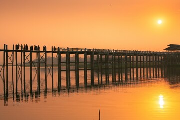 Fototapeta na wymiar The silhouettes of monks on a bridge at sunset in Myanmar