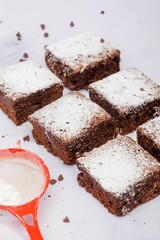 Freshly baked square pieces of chocolate brownie sprinkled with powdered sugar