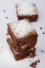 Freshly baked square pieces of chocolate brownie sprinkled with powdered sugar