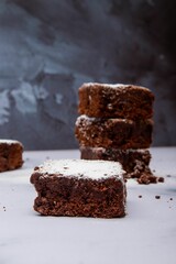 Freshly baked square pieces of chocolate brownie sprinkled with powdered sugar