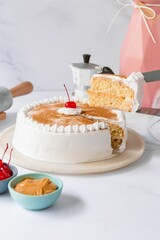 Delicious tres leches cake with ingredients on a marble table