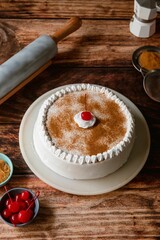 Delicious tres leches cake with ingredients on a wooden table