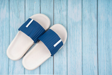 The Top view of white and blue color rubber slipper shoes on blue wooden background with copy space. Summer holiday vacation concept.