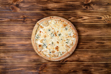 Pizza with four cheeses, mozzarella, blue cheese, Parmesan cheese. Italian cuisine. On a wooden background. View from above.