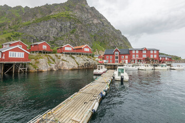 Obraz premium Charming fishing village A I Lofoten ( Å i Lofoten ) in Moskenesøya, with beautiful wooden red houses, small boats and surrounding mountains during summer on Lofoten islands, Norway.
