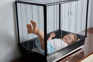 Todler's baby is lying in a cage.