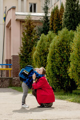 Young mother see of the child to school and hugs at farewell