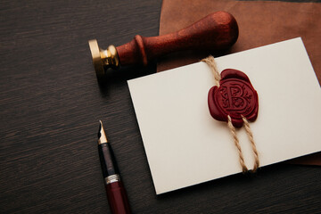 Fototapeta na wymiar Black envelope with red wax seal and stamp on dark wooden background