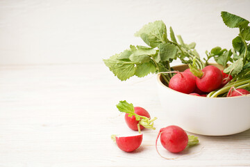 Ripe red radish in a bowl on a wooden background, space for text. Fresh red radish..