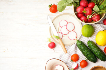 Radish and other spring vegetables on a wooden background, space for text, top view.