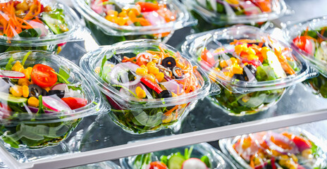 Boxes with pre-packaged vegetable salads in a commercial fridge