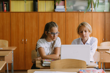 teen students working together using laptop in classroom