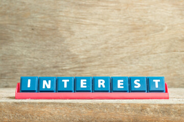 Tile letter on red rack in word interest on wood background