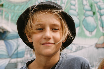 handsome teenage boy in hat osing at urban graffiti waal in hat