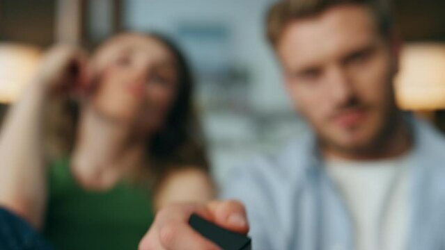 Focused pair staring tv show at home closeup. Man hand holding remote controller