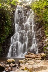 Soothing waterfall in the mountains, water stream falls from above from a rock onto stones