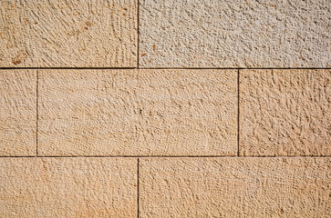 Fototapeta premium texture of a tiled beige stone wall as background, natural stone wall texture as background. Close-up of a wall clad in limestone