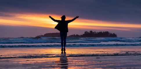 Adventurous Woman Standing on the Sandy Beach on the West Coast of Pacific Ocean. Cox Bay in Tofino, Vancouver Island, BC, Canada. Adventure Travel