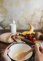 Two hands holding a bowl in the foreground. Breakfast cereal with nuts, oatmeal and fruit. Healthy snack or breakfast for a healthy lifestyle.