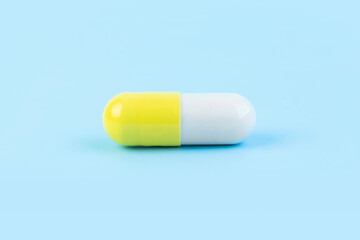 close-up of yellow gelatin capsules pill , oral medical drug filled with powder or liquid form on blue background, with copy space