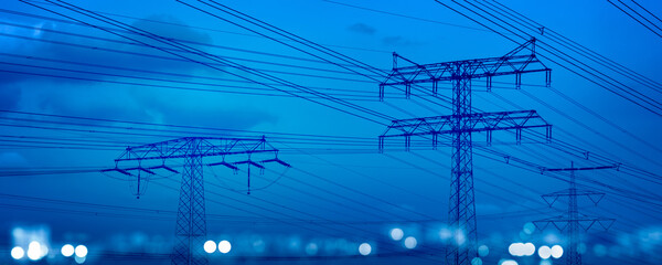 high-voltage tower and power lines with abstract defocused city lights at night, transmission of...