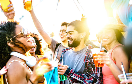 Trendy vacationers dancing at sunset concert on summer days - Fancy life style concept with guys and girls having genuine fun together at spring break party - Bright vivid filter with sunlight halo