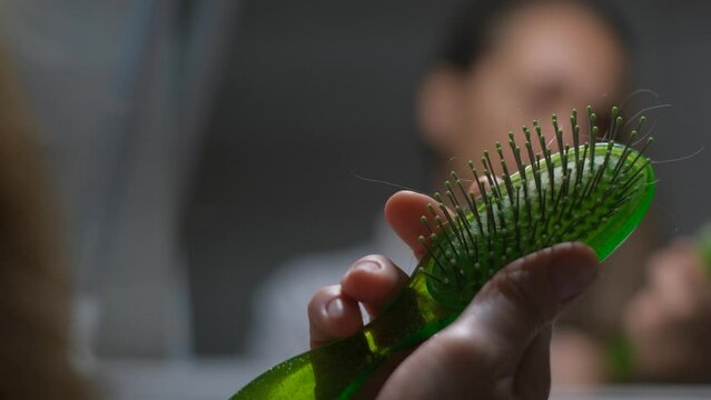 Comb with hair in the hands of a woman, close-up. Loss and hair loss