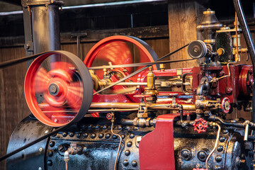 Vintage static steam engine running at full speed. Industrial Revolution.