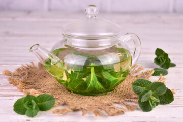 Mint tea with fresh mint leaves in a glass teapot.Close-up.
