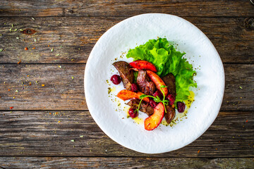 Fried liver with apples and onion on wooden table
