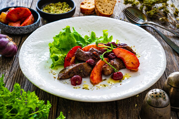 Fried liver with apples and onion on wooden table
