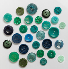 A lot of green and turquoise buttons of different sizes and shapes on a white background. Top view.