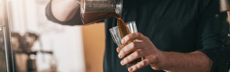 Barista pouring fresh made coffee to the glasses in coffee shop