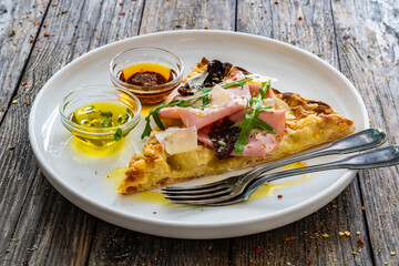 Pinsa Romana with mortadella, parmesan cheese and vegetables on wooden table
