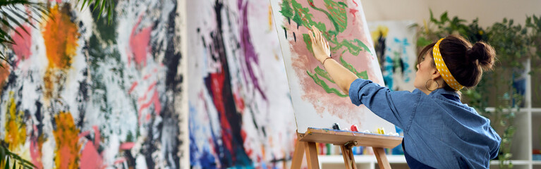 Inspired woman, female artist in apron creating abstract painting at home studio workshop