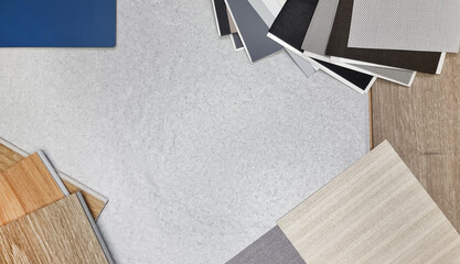combination of interior material board samples contains roller blind drapery swatch, wooden vinyl flooring tile, interior fabric wallpaper, blue laminate in top view with blank space at center.