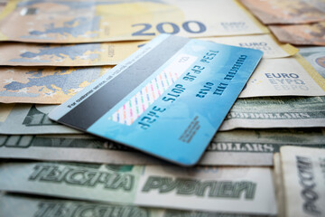 payment card on background of paper dollars. blue plastic multicurrency credit card is lying on stack of money euros rubles and dollars