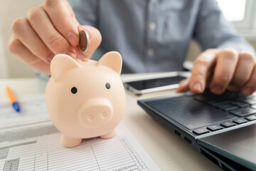 Finance home accounting. Saving money concept. Man hand putting coin drop into piggy bank and...