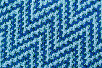 Knitted texture with zigzag pattern. Texture of mosaic fabric with blue geometric ethnic pattern. Crochet mosaic pattern.