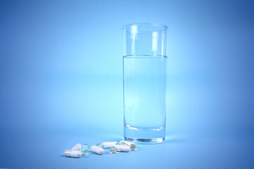 Pills and a glass of water on the table. drinking water and taking medications (pills) - they will strengthen your body during illness