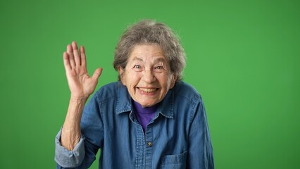 Waving to friend meet greet, portrait of happy smiling elderly senior old woman with wrinkled skin and grey hair isolated on green screen background.