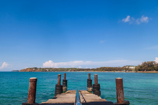 a picturesque pier at the rafai beach pier going under water with steps. Clear turquoise water and blue sky. Travel and recreation.