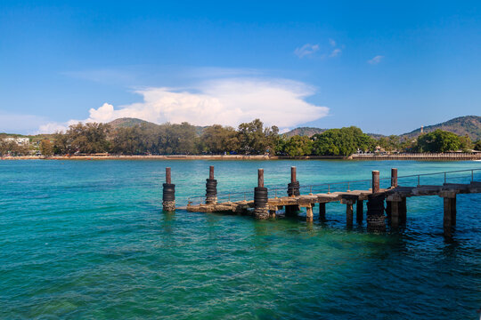 a picturesque pier at the rafai beach pier going under water with steps. Clear turquoise water and blue sky. Travel and recreation.
