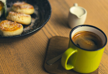 Syrniki with caramel pear and coffee cup. Curd cottage pancakes with coffee and milk. Delicious breakfast. Ukrainian food. Cheese pancakes and mug of coffee. Restaurant menu. Homemade dessert.