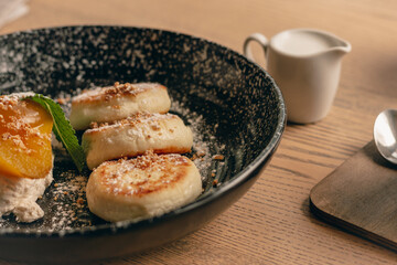 Syrniki with caramel pear and coffee cup. Curd cottage pancakes with coffee and milk. Delicious breakfast. Ukrainian food. Cheese pancakes and mug of coffee. Restaurant menu. Homemade dessert.