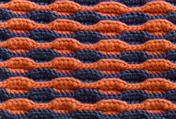 Knitted background. Crochet orange purple volume wave pattern.
