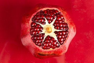 Sliced ripe pomegranate on a red background.