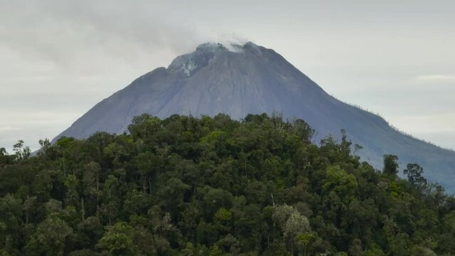 Aerial view of volcano Sinabung with clouds and smoke and jungle. Sumatra, Indonesia.