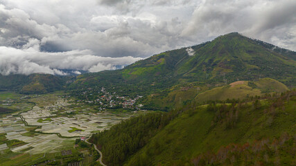 Fototapeta premium Aerial drone of farmland and town in the valley among the mountains. Sumatra, Indonesia.