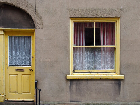 front view of a typical old small english terraced house with yellow painted door and window